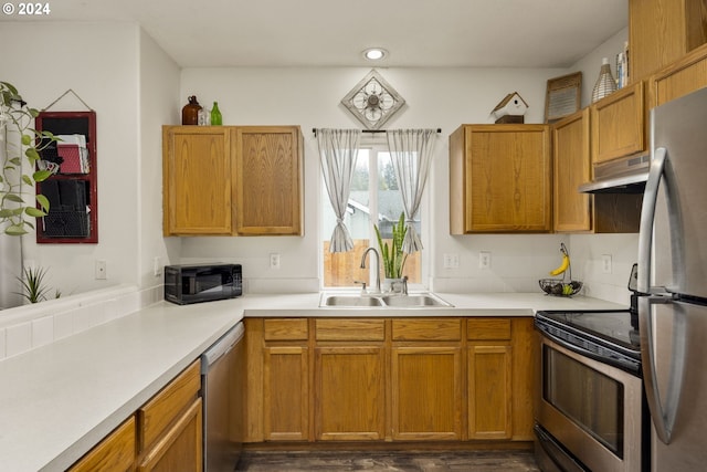 kitchen featuring black appliances, dark hardwood / wood-style floors, ventilation hood, and sink