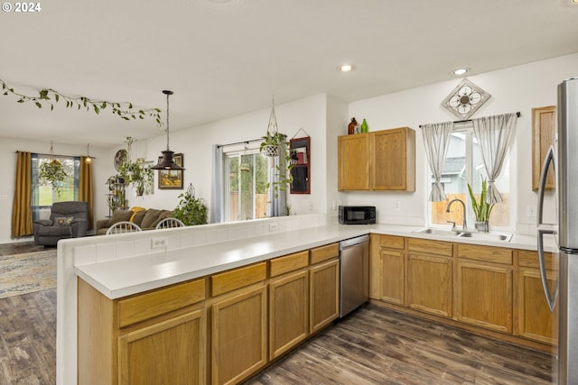 kitchen featuring sink, stainless steel appliances, dark hardwood / wood-style flooring, kitchen peninsula, and pendant lighting