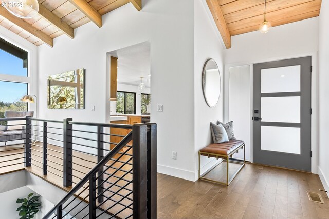 foyer entrance featuring vaulted ceiling with beams, dark wood-type flooring, and wooden ceiling