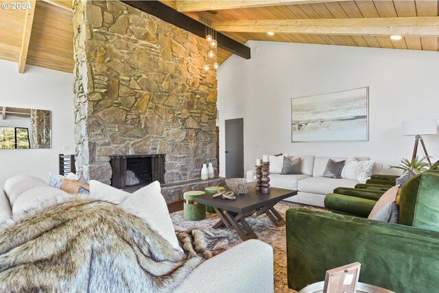 living room with beam ceiling, a stone fireplace, high vaulted ceiling, and wooden ceiling