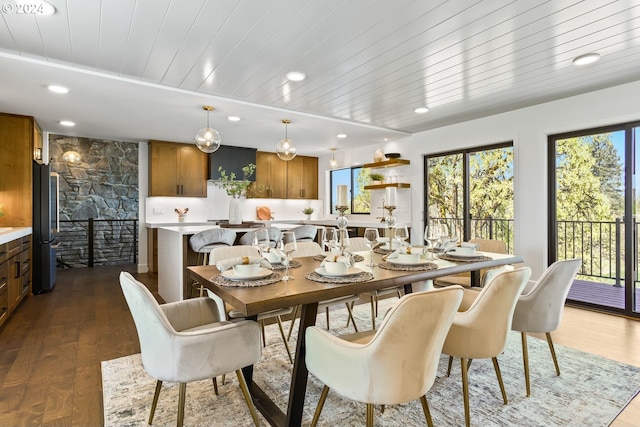 dining area with a stone fireplace, wood ceiling, and dark hardwood / wood-style floors