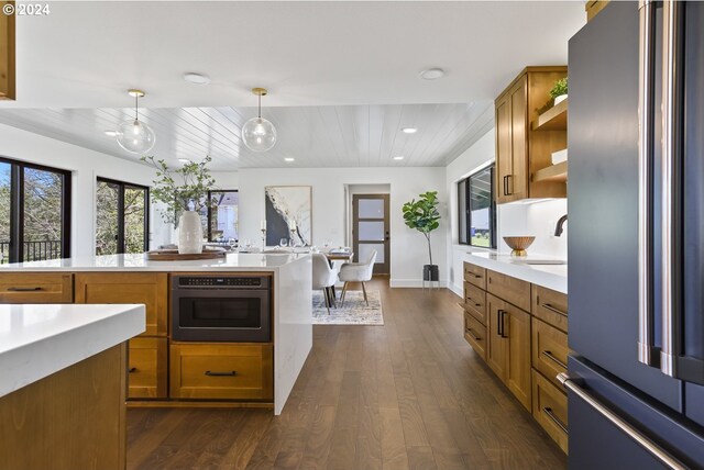 kitchen featuring stainless steel refrigerator, sink, dark wood-type flooring, oven, and decorative light fixtures