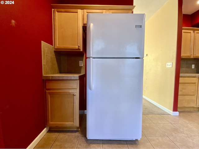 kitchen featuring decorative backsplash, light tile patterned floors, and white refrigerator