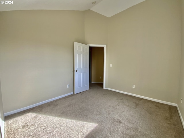 carpeted empty room with high vaulted ceiling