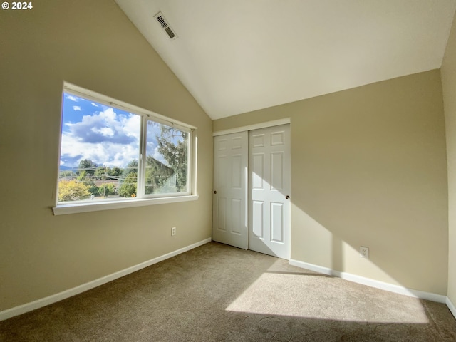 unfurnished bedroom with lofted ceiling, light colored carpet, and a closet