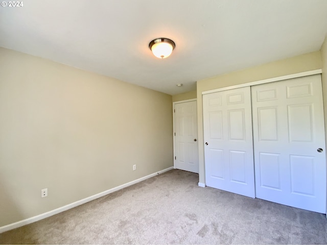 unfurnished bedroom featuring light colored carpet and a closet