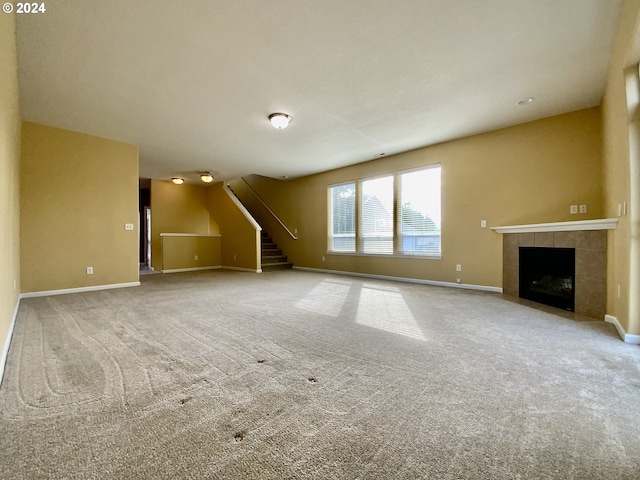 unfurnished living room featuring carpet flooring and a tile fireplace