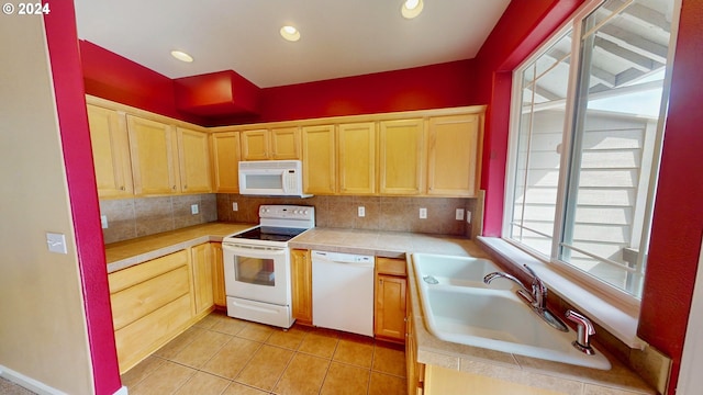 kitchen with sink, light tile patterned floors, white appliances, light brown cabinetry, and decorative backsplash