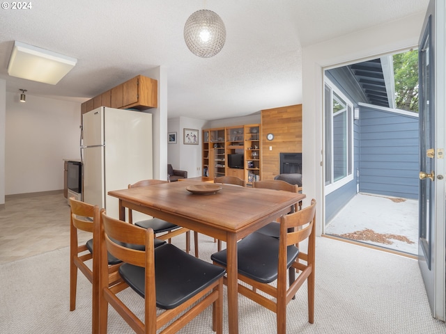 carpeted dining room featuring wooden walls and a textured ceiling