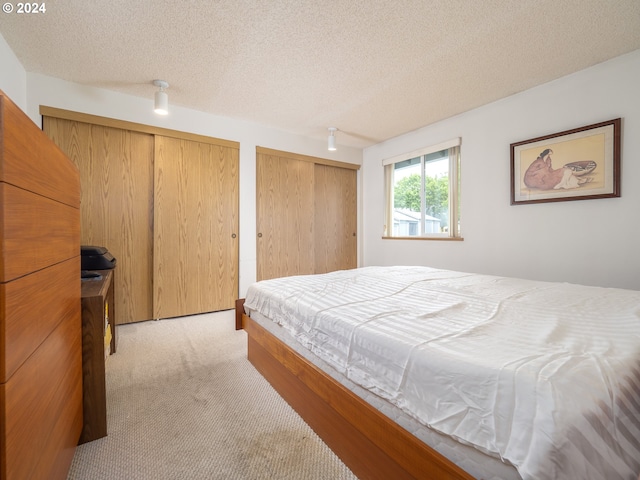 carpeted bedroom with multiple closets and a textured ceiling