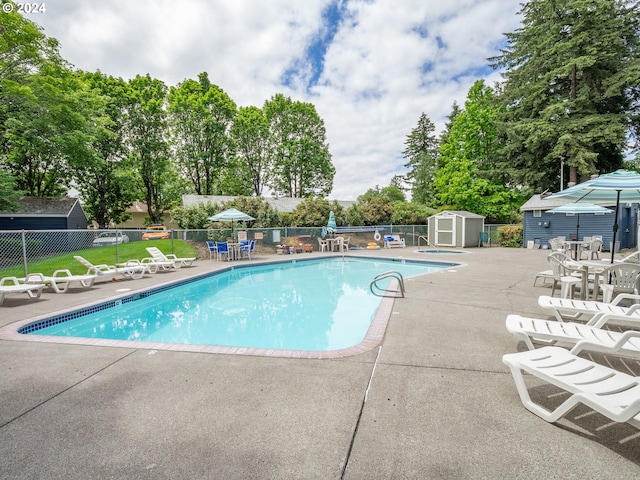 view of swimming pool with a storage shed and a patio