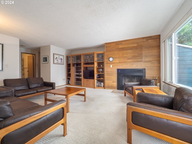 living room featuring wooden walls, a fireplace, light colored carpet, and a textured ceiling