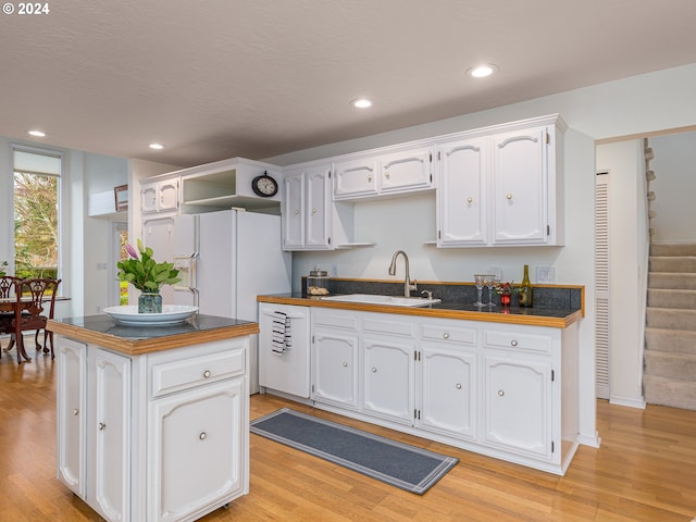 kitchen with white cabinetry, sink, light hardwood / wood-style floors, white appliances, and a kitchen island