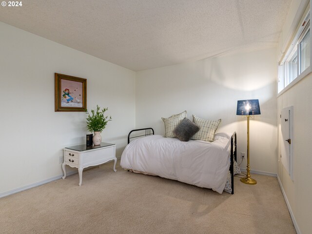 bedroom featuring light carpet and a textured ceiling