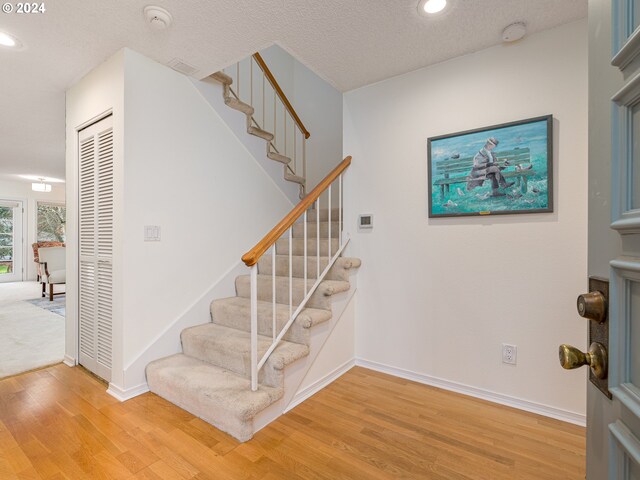 staircase with hardwood / wood-style floors and a textured ceiling