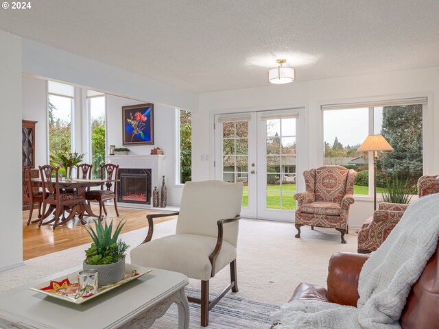 living room featuring light hardwood / wood-style floors, a premium fireplace, a textured ceiling, and french doors