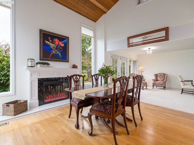 dining area with high vaulted ceiling, wood ceiling, a high end fireplace, and light hardwood / wood-style flooring