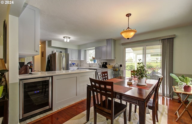 dining area with beverage cooler and wood finished floors