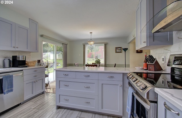 kitchen with tasteful backsplash, a peninsula, gray cabinets, stainless steel appliances, and under cabinet range hood