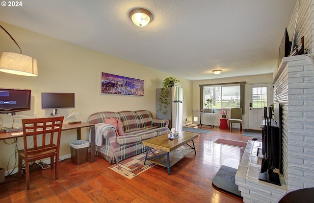 living area featuring a fireplace, wood finished floors, and baseboards