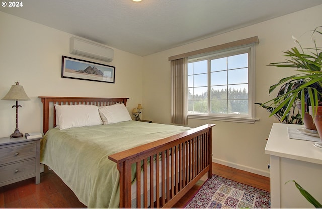 bedroom featuring baseboards, dark wood-style flooring, and a wall mounted AC