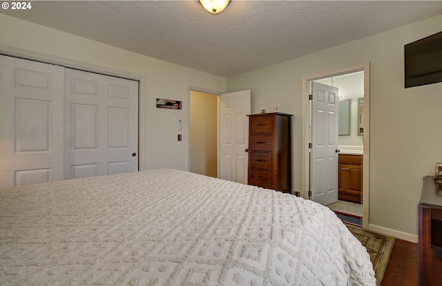 bedroom featuring baseboards, ensuite bath, wood finished floors, a textured ceiling, and a closet