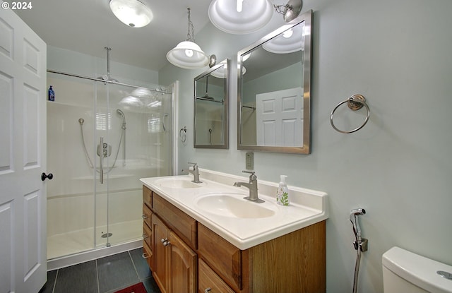 full bath with toilet, a stall shower, double vanity, and a sink