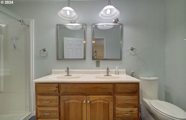 full bathroom featuring toilet, double vanity, walk in shower, and a sink