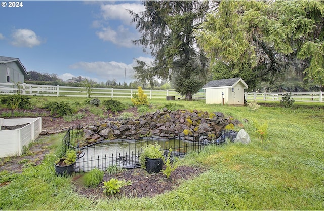 view of yard featuring a storage unit, a rural view, an outdoor structure, and fence