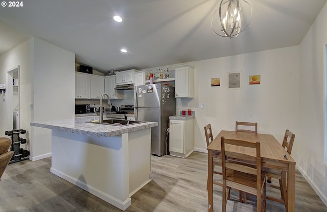 kitchen with light wood-style floors, freestanding refrigerator, a sink, and under cabinet range hood