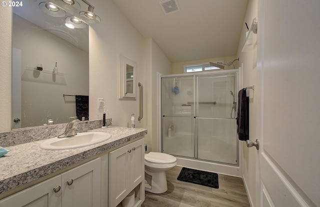 bathroom with visible vents, toilet, a stall shower, vanity, and wood finished floors