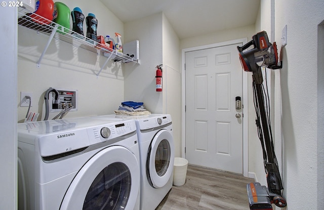 clothes washing area with laundry area, light wood finished floors, and washer and dryer