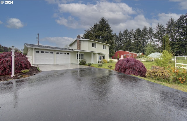 view of front of property featuring a garage, driveway, and fence