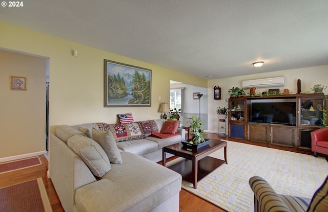 living room featuring wood finished floors, baseboards, and a wall mounted AC