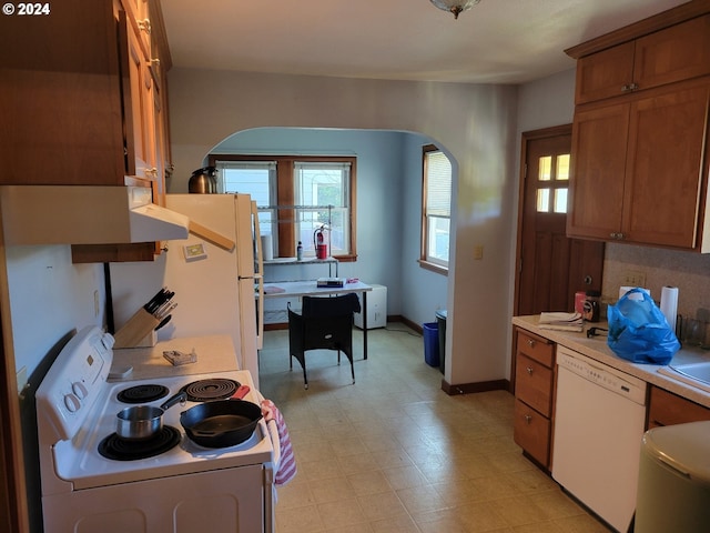 kitchen with light tile flooring, white appliances, and backsplash