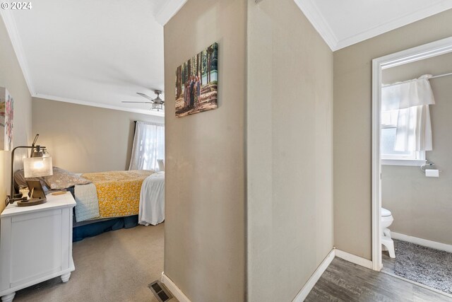 bedroom featuring dark colored carpet, ensuite bathroom, crown molding, and ceiling fan