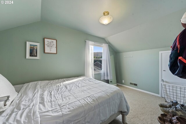 bedroom with light carpet and lofted ceiling