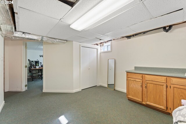 basement with dark colored carpet and a drop ceiling