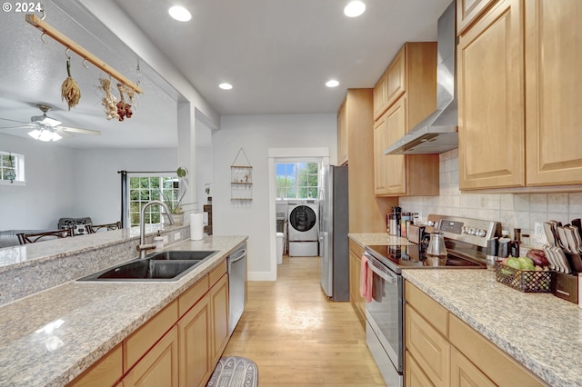 kitchen featuring sink, wall chimney range hood, stainless steel appliances, and plenty of natural light