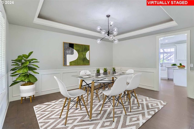 dining area featuring dark hardwood / wood-style flooring, a tray ceiling, and a notable chandelier