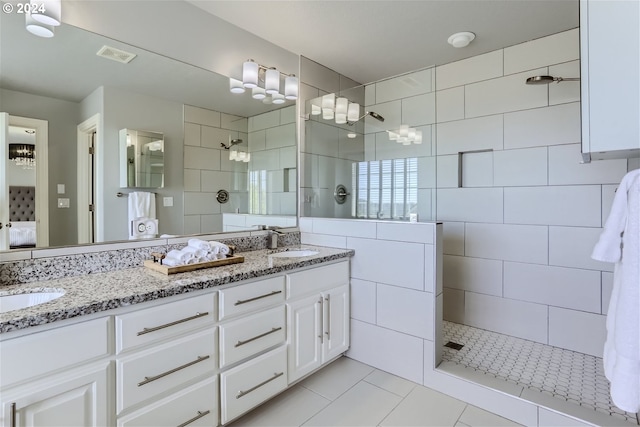 bathroom with tile patterned floors, vanity, and tiled shower