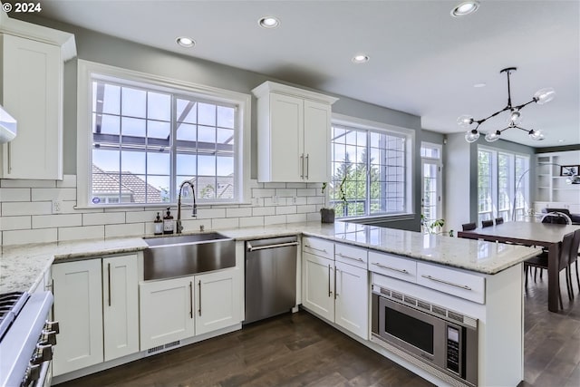 kitchen featuring sink, kitchen peninsula, pendant lighting, white cabinets, and appliances with stainless steel finishes