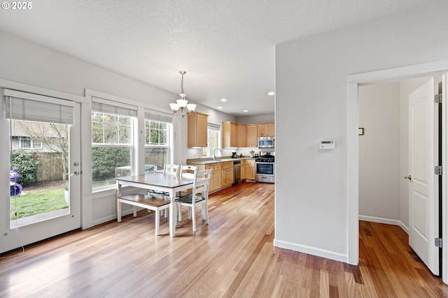 dining area featuring a textured ceiling, recessed lighting, a notable chandelier, baseboards, and light wood finished floors