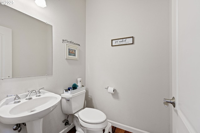 half bathroom with a sink, toilet, and baseboards