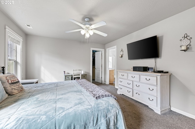 carpeted bedroom featuring ceiling fan, a walk in closet, visible vents, and baseboards