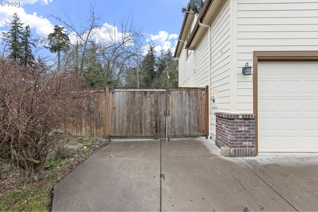 view of property exterior featuring a garage, brick siding, and fence