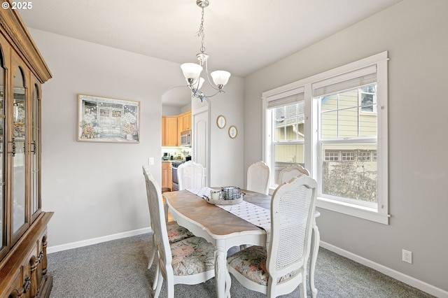 carpeted dining space featuring plenty of natural light, an inviting chandelier, and baseboards