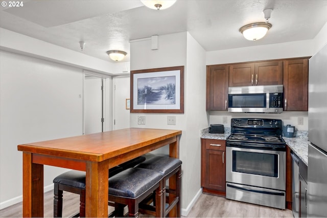 kitchen featuring light stone countertops, stainless steel appliances, and light hardwood / wood-style floors