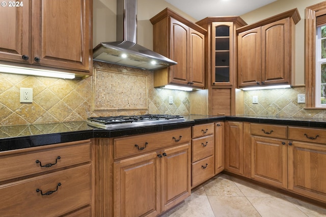 kitchen featuring light tile patterned floors, wall chimney exhaust hood, stainless steel gas cooktop, and tasteful backsplash