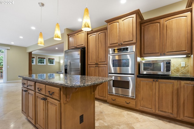 kitchen with appliances with stainless steel finishes, dark stone countertops, decorative light fixtures, a kitchen island, and decorative backsplash